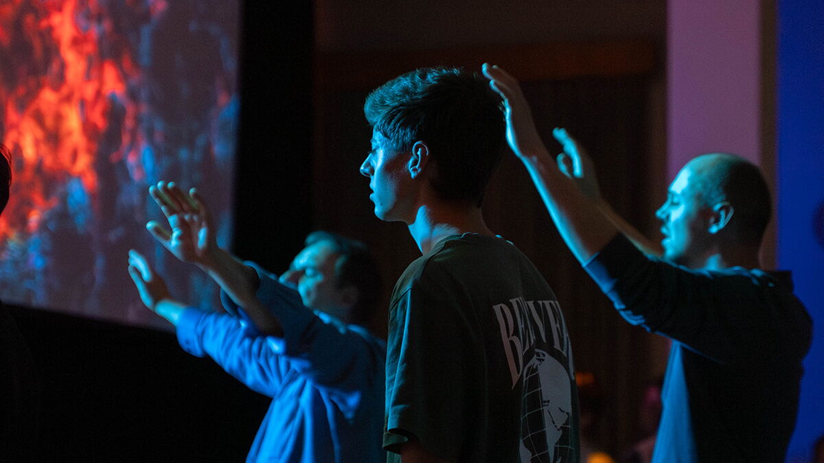 Drei Menschen bei Lobpreis und Anbetung - zwei haben die Hände erhoben.