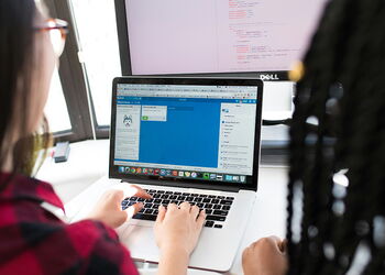 Zwei Personen sitzen vor einem aufgeklappten Notebook