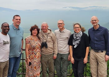 Eine Gruppe von Menschen stehen vor Hügelketten in Tansania.