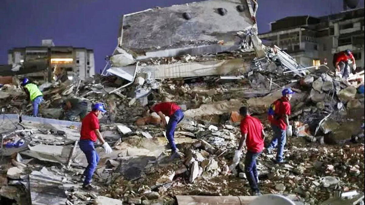 Einsatzkräfte klettern über Schuttberge in der Dunkelheit im Erdbebengebiet in Venezuela.