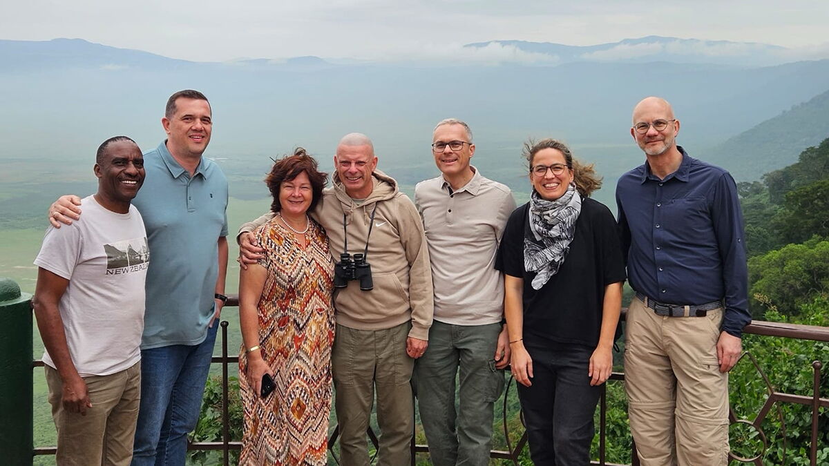 Eine Gruppe von Menschen stehen vor Hügelketten in Tansania.