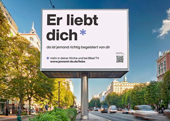 Großplakat in einer Stadt mit der Aussage "Er liebt dich".