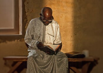 Ein älterer Mann sitzt in einer Kirche in Jos, Nigeria, und liest in einer aufgeschlagenen Bibel.