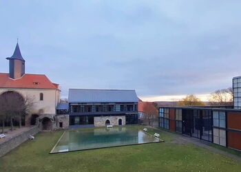Blick auf die Klosteranlage in Volkenroda im Morgenlicht mit der Kapelle im Hintergrund.