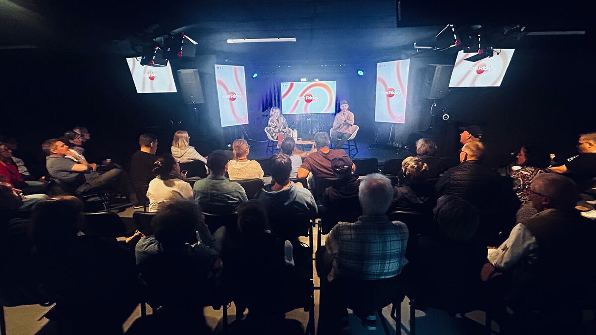 Eine Gruppe von Menschen sitzt in einem Veranstaltungsraum und hört zwei Gesprächspartnern auf einer Bühne zu, die im Rahmen einer Begegnung während der Israel-Studienreise sprechen.