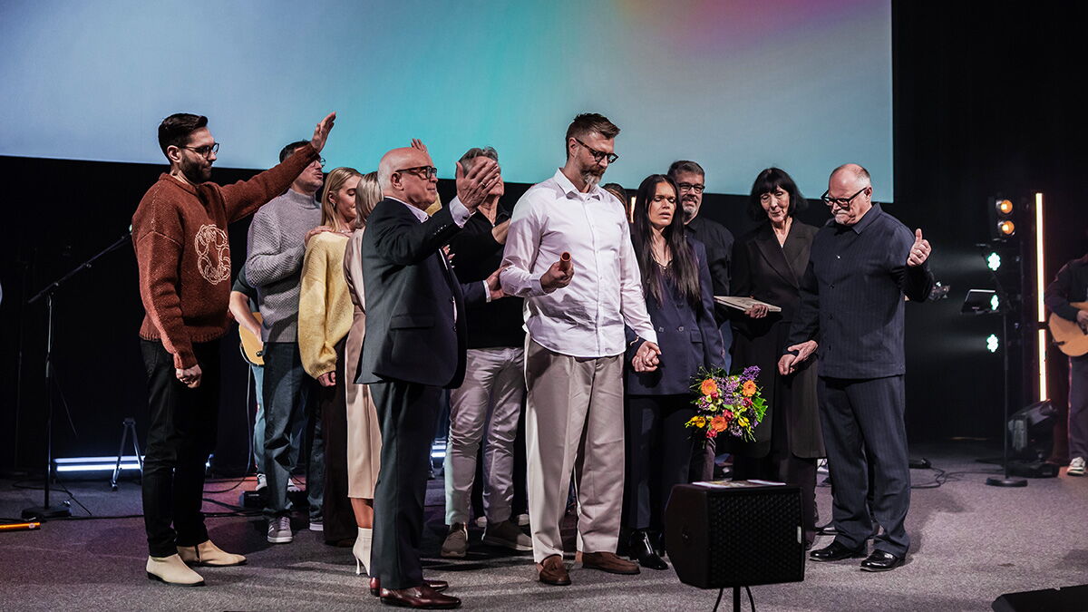 Menschen stehen auf einer Bühne und beten für ein Paar in der Mitte.