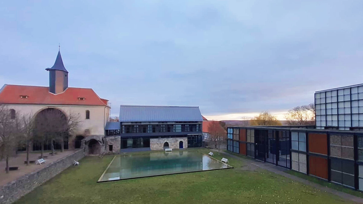 Blick auf die Klosteranlage in Volkenroda im Morgenlicht mit der Kapelle im Hintergrund.